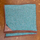 Folded teal fabric with brown border on a scratched LEATHER surface