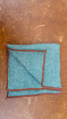 Teal fabric with brown border on a scratched LEATHER surface
