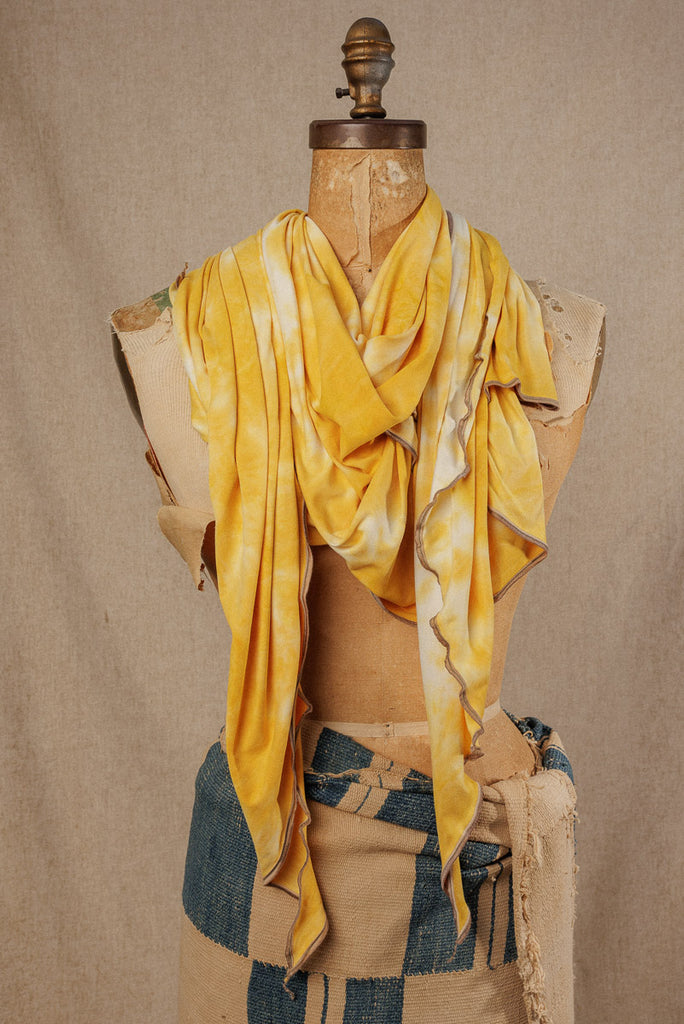 a bright yellow tie dye scarf draped around the neck of a mannequin