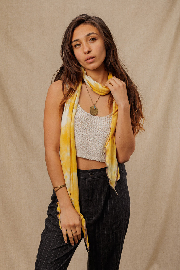 a woman wearing a a bright yellow tie dye scarf wrapped around her neck