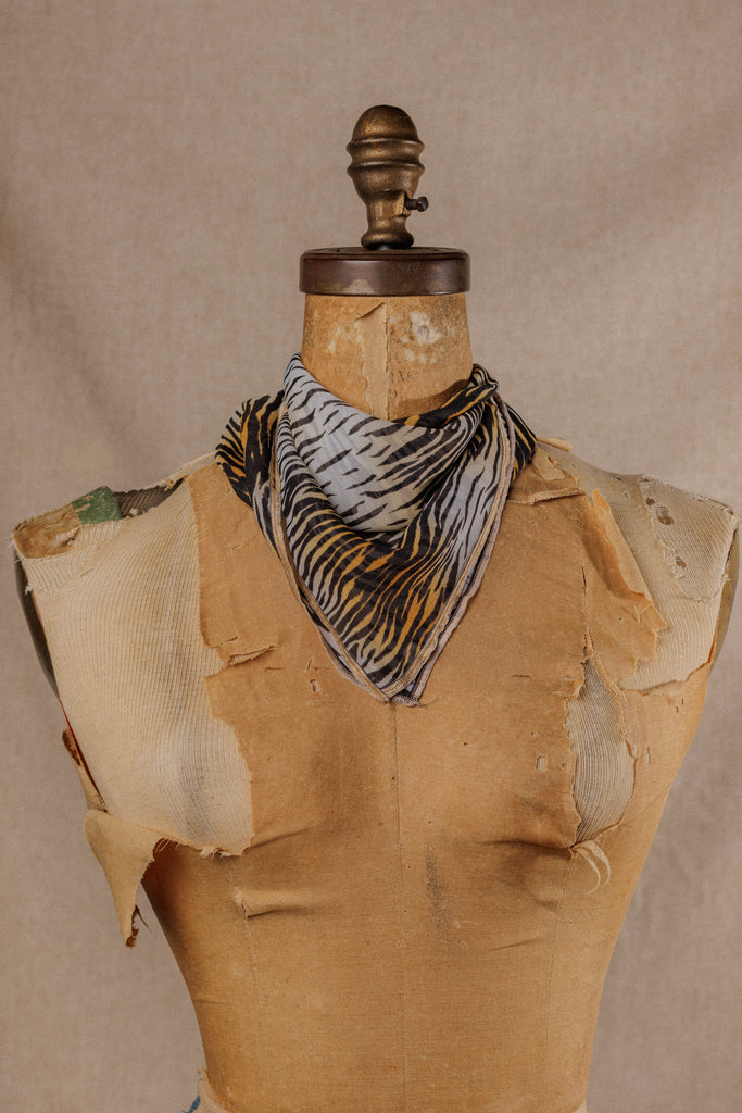 a tiger stripe motif bandana displayed around the neck of a muslin mannequin 
