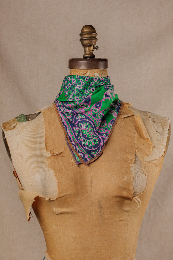 a green bandana with blue and purple floral motif displayed around the neck of a mannequin
