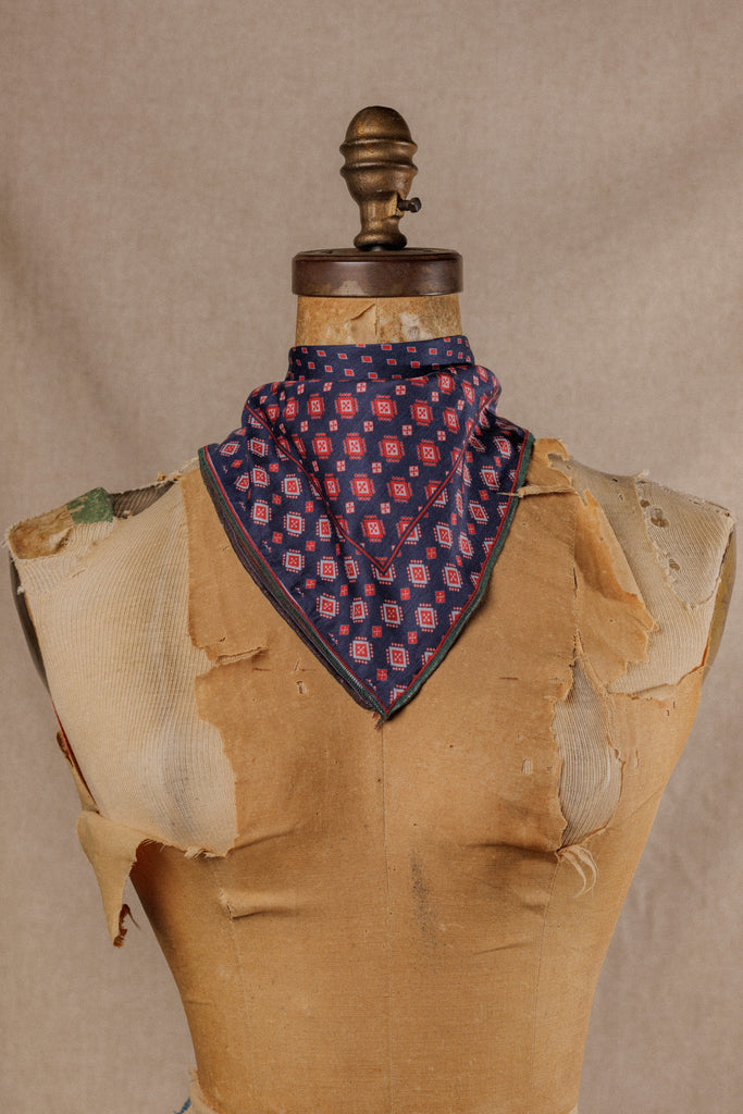  a bandana with a geometric blue and red motif displayed around the neck of a mannequin
