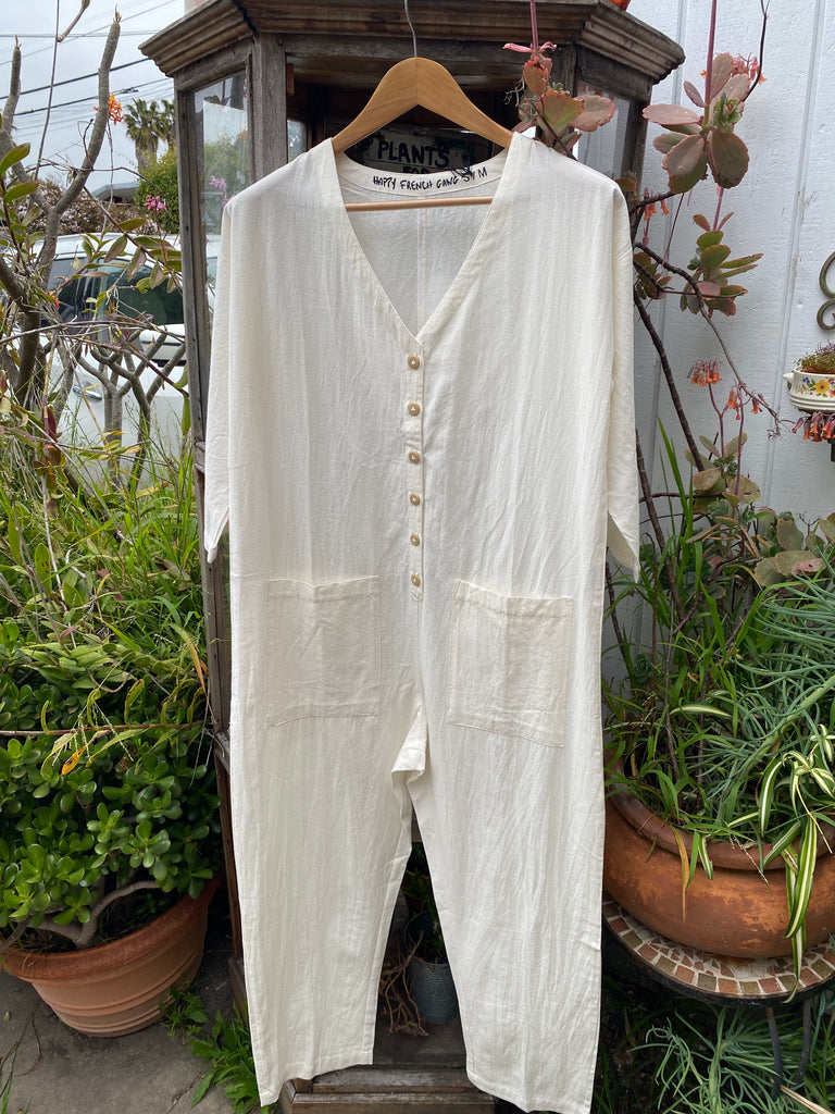 a cream colored long sleeve jumpsuit displayed on a hanger
