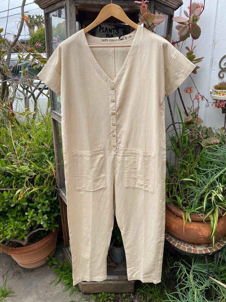 a cream colored short sleeve jumpsuit displayed on a hanger