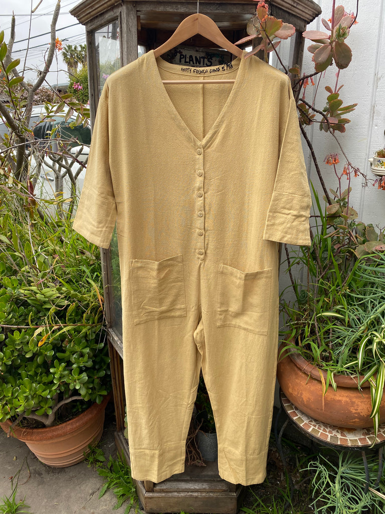a light mustard colored  long sleeve jumpsuit displayed on a hanger
