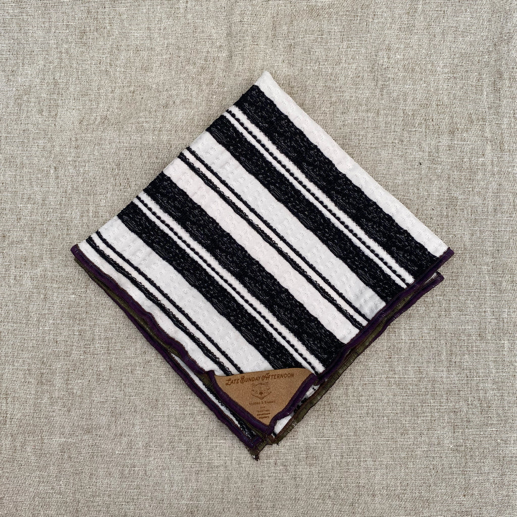 a black and white motif handkerchief shown folded with a small brown tag in the corner