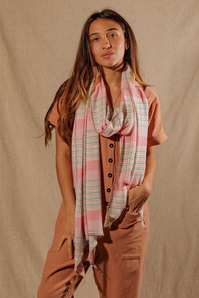 a woman wearing a pink, white, and green striped scarf wrapped around her neck