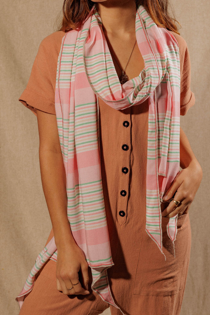 closeup of a woman wearing a pink, white, and green striped scarf wrapped around her neck
